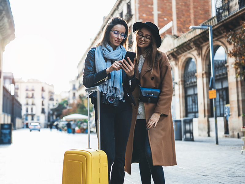 Junge Reisende nutzen Smartphone mit digitaler Kartenansicht zur mobilen Planung einer Fahrt &uuml;ber eine Taxi App in Offenbach.